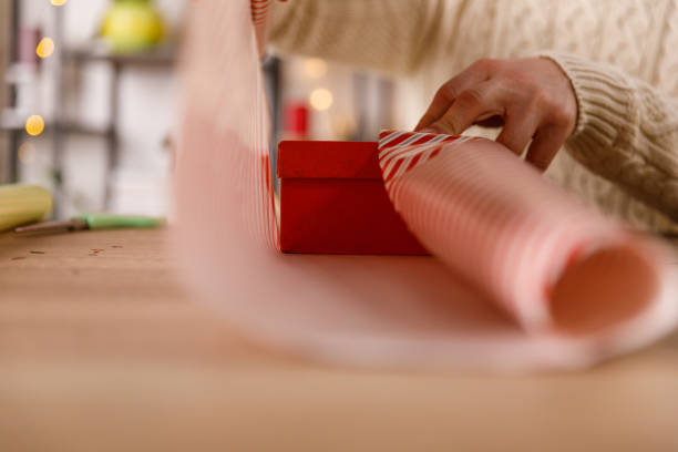 istock Man wrapping a little red gift box in a wrapping paper 1468924839