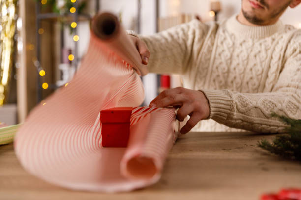 istock Man wrapping a little red gift box in a wrapping paper 1468924850