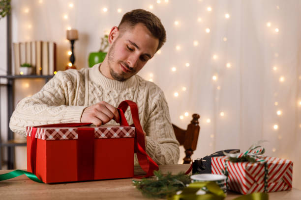 istock Young man wrapping a red ribbon around a Christmas gift box 1468925284