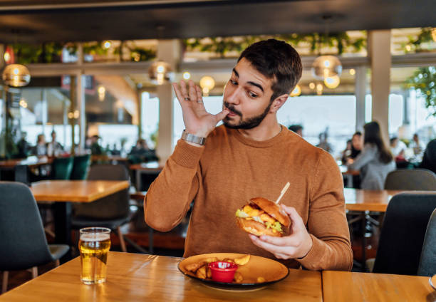 młody człowiek delektujący się pysznym burgerem - finger licking zdjęcia i obrazy z banku zdjęć