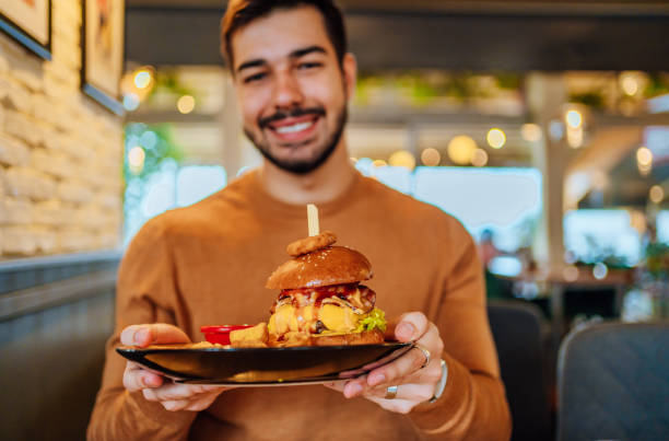 istock Young man holding a plate with a tasty burger 1468927263