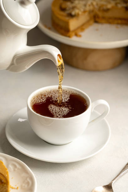 istock Pouring hot tea in white, ceramic cup, served with cake 1468927400