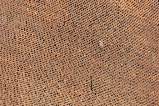 This image shows a close-up full frame texture background view of an attractive speckled brown and white brick wall, in traditional running bond brickwork pattern.