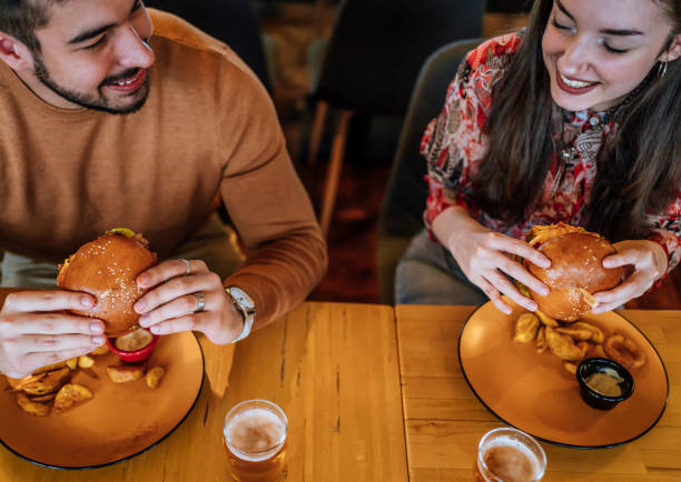 istock Couple enjoying at the restaurant while eating burgers 1468928461