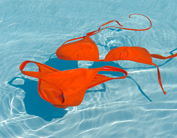 Bikini swim suit in water of swimming pool Photograph of orange bikini in clean water. Women's swim suit floating in blue swimming pool of a sea spa tourist resort. swimwear bikini top bikini bikini bottom stock pictures, royalty-free photos & images