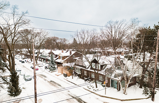 City neighbourhood during winter with snow. Early morning in  North American city with fresh snow on the ground and roof tops. View point of the drone from the air.