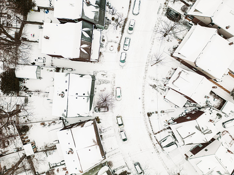 City neighbourhood during winter with snow. Early morning in  North American city with fresh snow on the ground and roof tops. View point of the drone from the air.