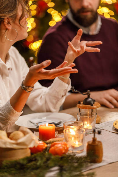 Young woman gesturing while sharing an interesting story with friends during a Christmas dinner party