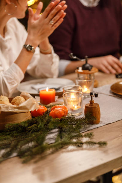 Close up shot of tea candles burning on a dining table, next to rustic decorations, making atmospheric mood during a Christmas dinner party.