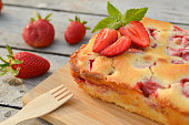 Delicious summer dessert strawberry pie, sweet homemade holiday cake decorated with mint leaves on a light wooden table.