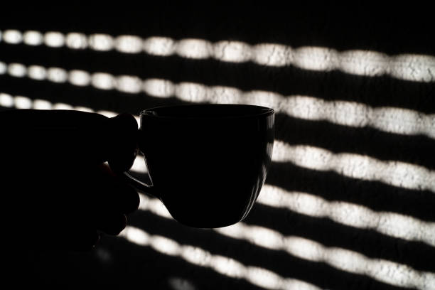 White cup of black coffee on concrete table with shadow.