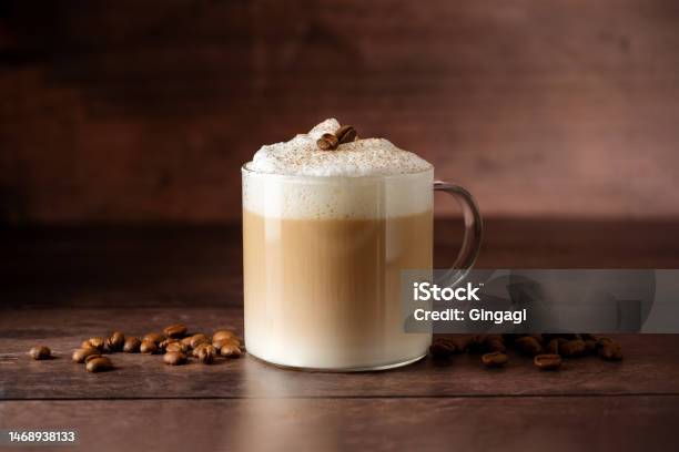Glass Cup Of Layered Coffee Drink With Milk Foam Coffee Beans Over Wooden Background Copy Space Stock Photo - Download Image Now
