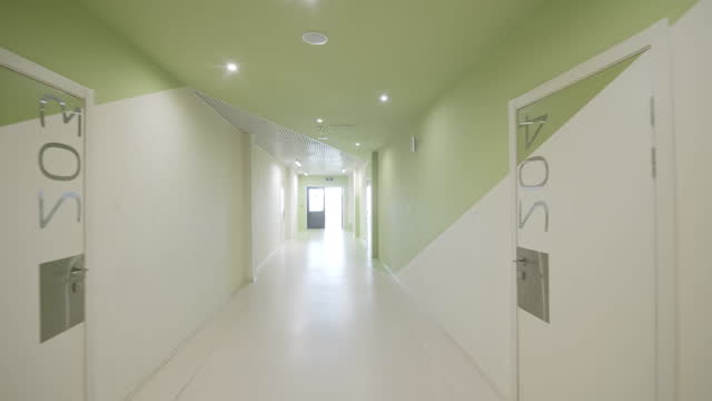 Long light corridor with switchboards and numbered rooms