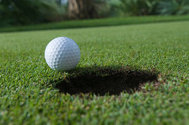 istock Golf ball at putting hole in green grass 146894044