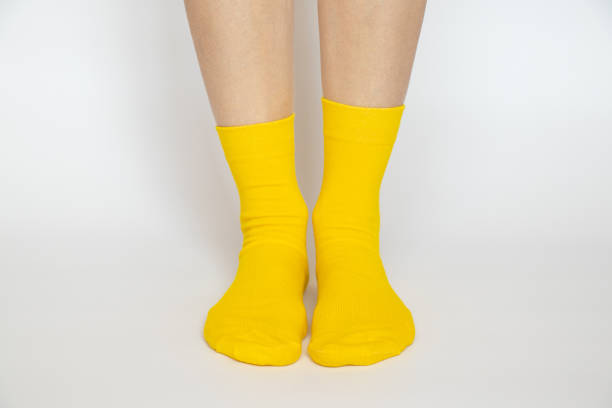 istock Women's legs in yellow socks on a white background 1468943268