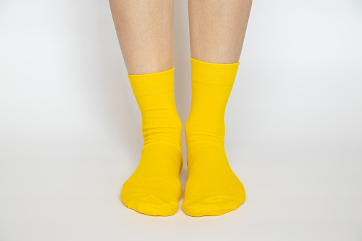 Women's legs in yellow socks on a white background close -up