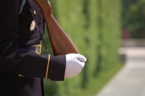 Close up showing the uniform, gloved hand, and rifle of a soldier standing guard at the Tomb of the Unknown Soldier at Arlington National Cemetary, Washington D.C.
