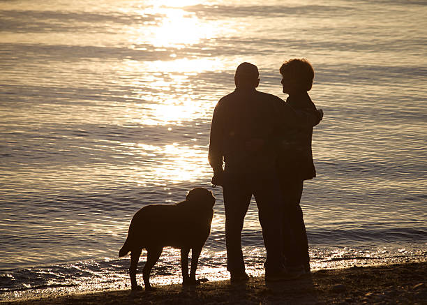 man and a woman couple on the beach sunset sky on sea or ocean. orange sunlight, peace, walk. Silhouettes of people against sky seascape. Calendar poster. People's relationships, tourist destinations