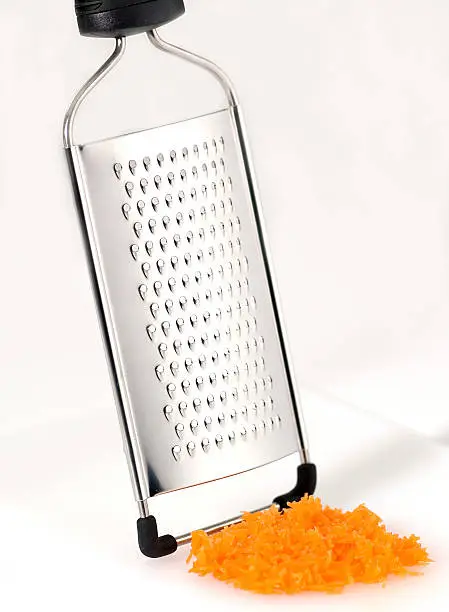 Chrome cheese grater with cheese on a white background.