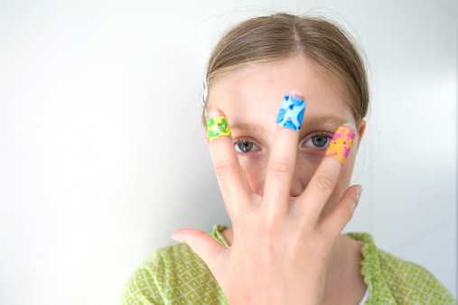 girl with coloful adhesive plasters on her fingers (focus on eyes)