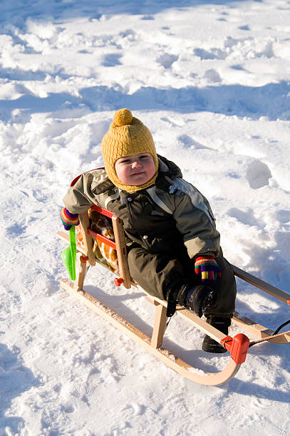istock Baby in green coat sitting on sled 146895411