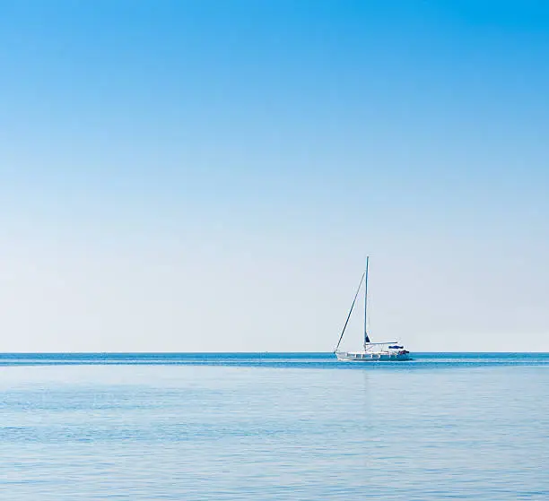 Stock photo of a sailboat in Adriatic sea. Blue sky over water horizon. Copyspace background.