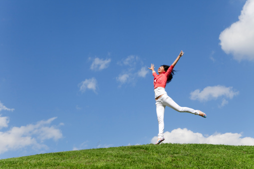 pretty young woman jumping on green grass