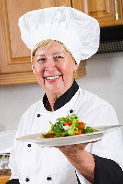 istock senior female chef presenting salad 146896278