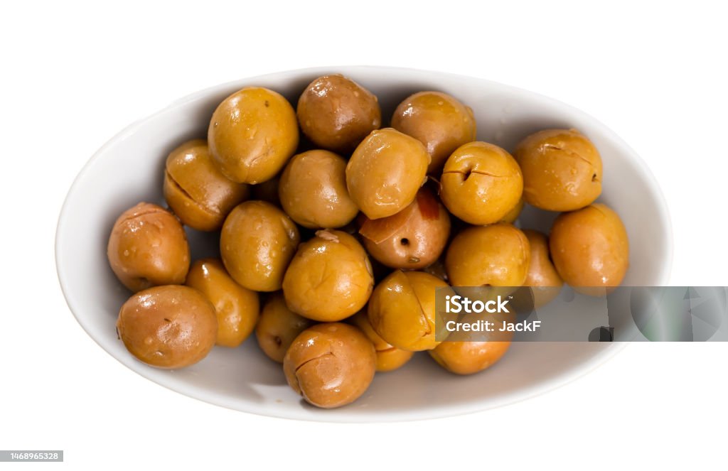 Serving of fresh pitted olives on plate Fresh green olives with pits served on plate. Isolated over white background Appetizer Stock Photo