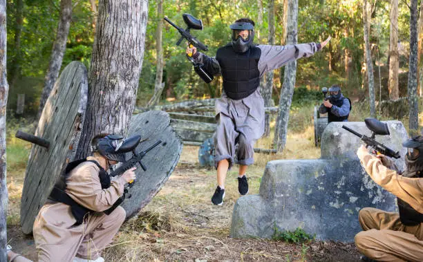 Paintball team rushing enemy positions on battleground during training outdoors.