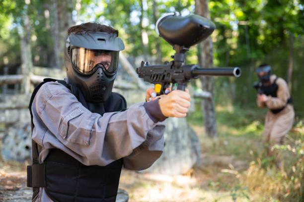 istock Paintball player in protective uniform aiming and shooting with guns 1468966496
