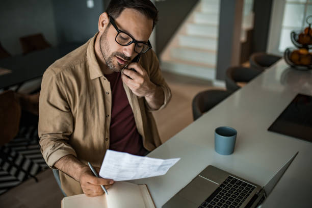 istock Young man working on financial bills and calling financial advisor at home. 1468966643