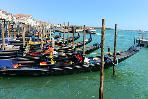 Beautiful landscape of gondolas on the canal and historical buildings of Venice, The gondolas moored at the coast of the Grand channel (Canal Grande) waiting for passengers.