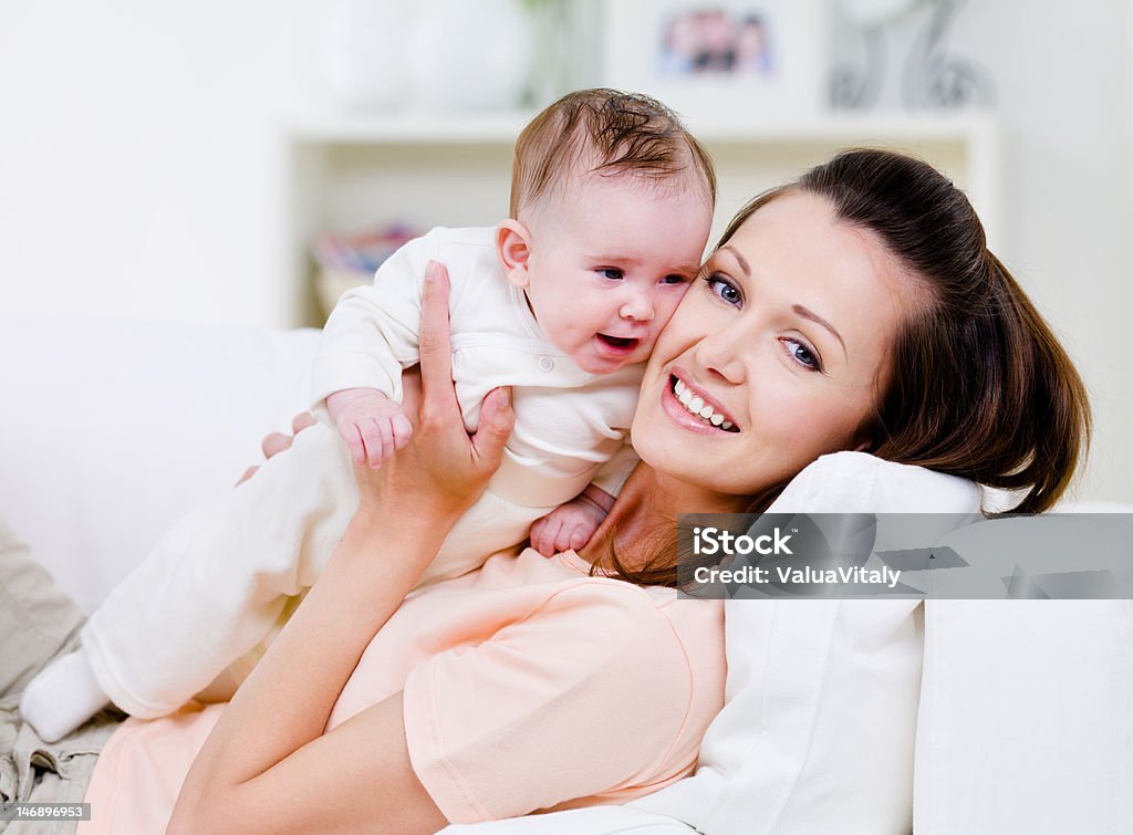 Happy mother with little baby Young smiling happy mother with little baby on the sofa - indoors Adult Stock Photo