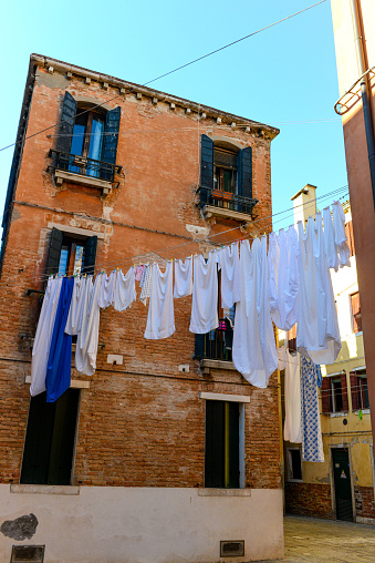 Typical city corner with ancient colorful buildings Drying clothes on a clothes-line in outdoor at sunny summer day. Venice, Italy.