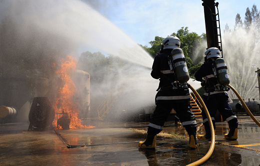 Firefighters Extinguishing hard working to fix Fire ,Fireman wearing firefighter turnouts and helmet.  Advant Fire Fighting and Fire Drill Training