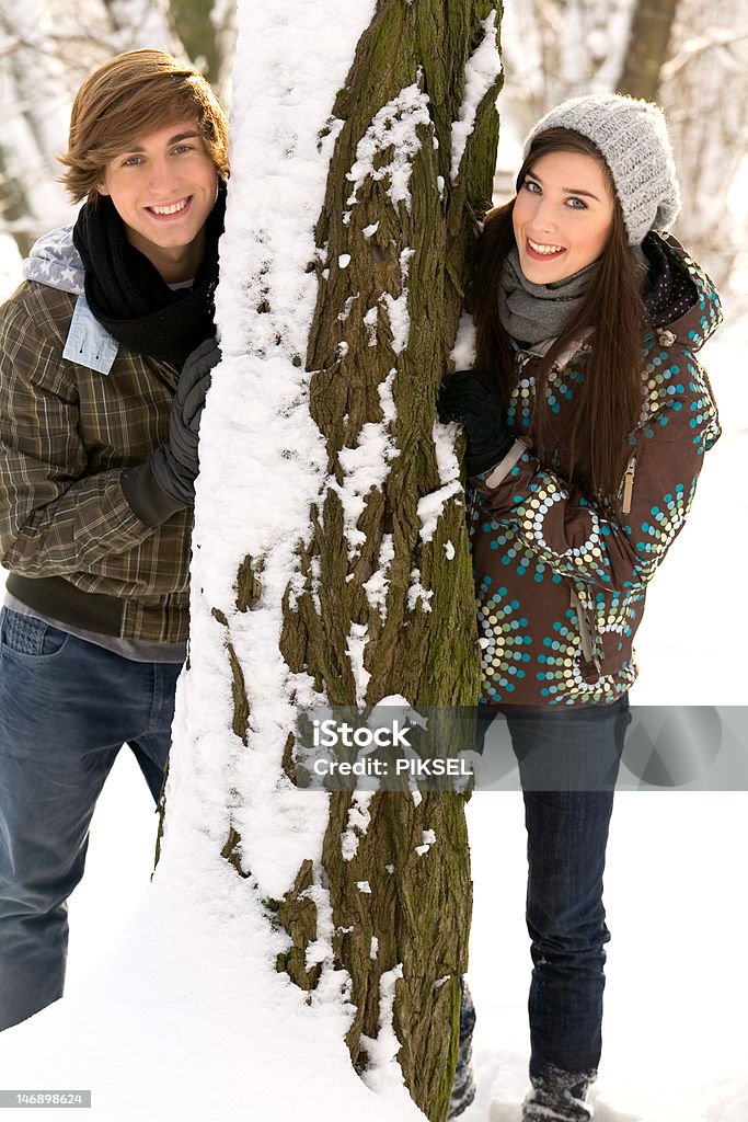 Coppia all'aperto con albero sorridente - Foto stock royalty-free di Abbigliamento