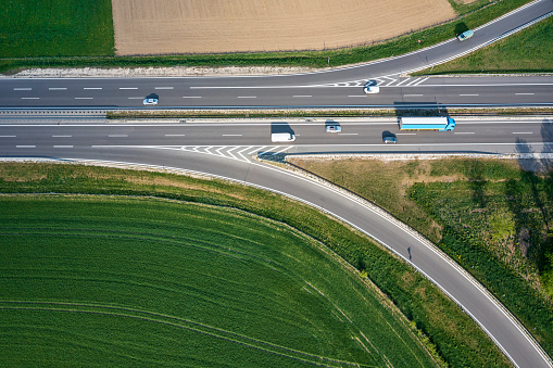 Aerial view of multiple lane highway intersection with cars and truck.