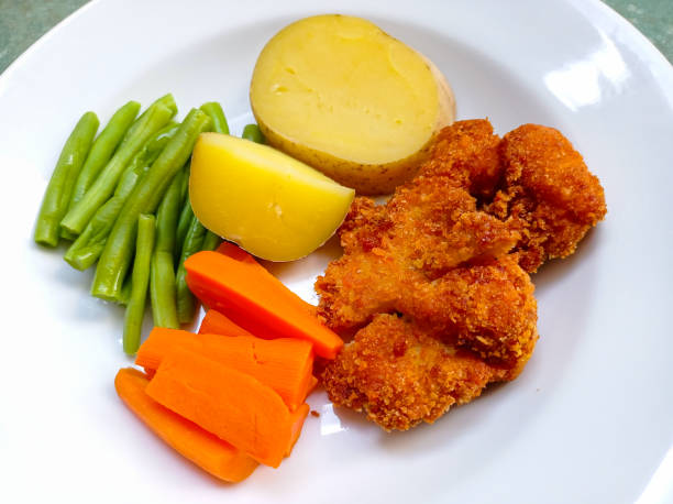 istock Breaded German Weiner Schnitzel served on a white plate with boiled vegetables (potatoes, chickpeas and carrots). 1468996724