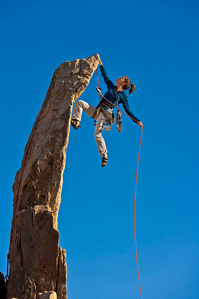 Climber clings to the edge of a rock pinnicle in the remote Mojave Desert of California.