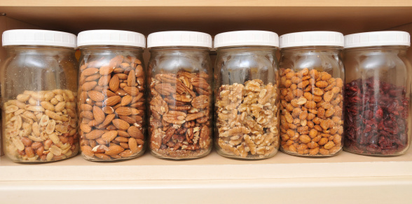 Healthy Nuts in Glass Jars sitting on a shelf.