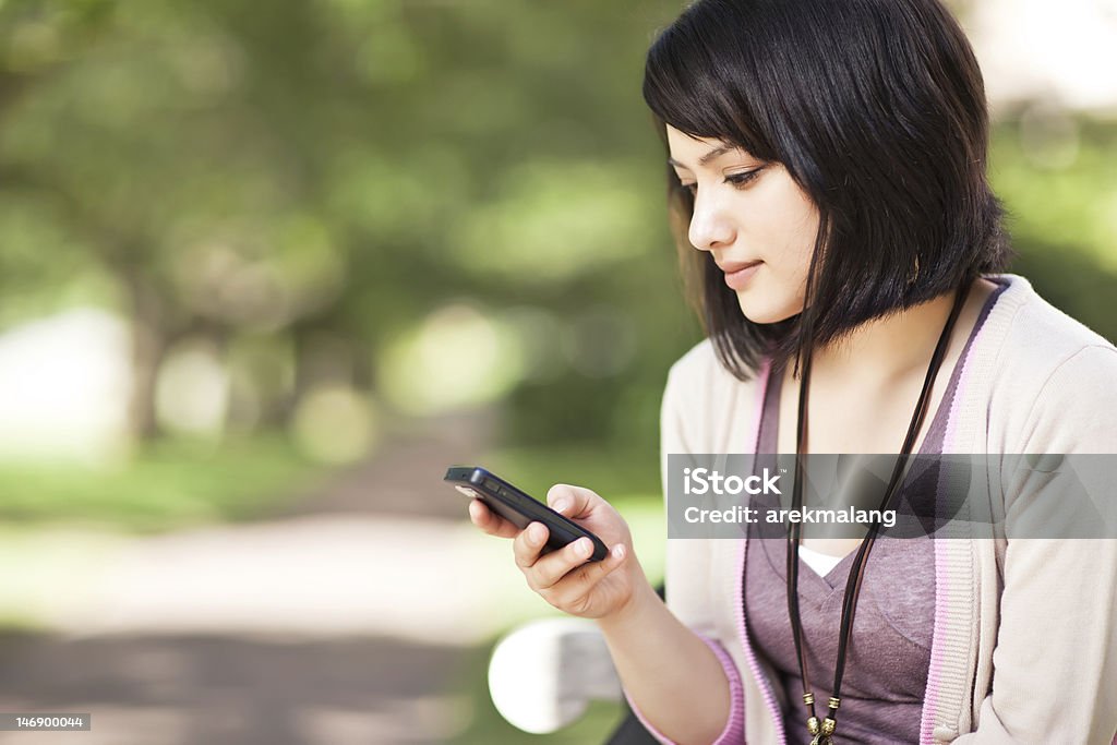 Mixed race student texting A shot of a mixed race girl texting on the phone at campus Adolescence Stock Photo