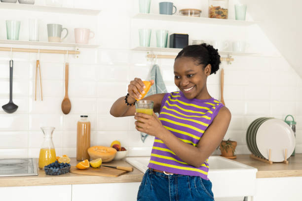 istock Happy African young woman squeezing an orange and making fresh juice 1469001414