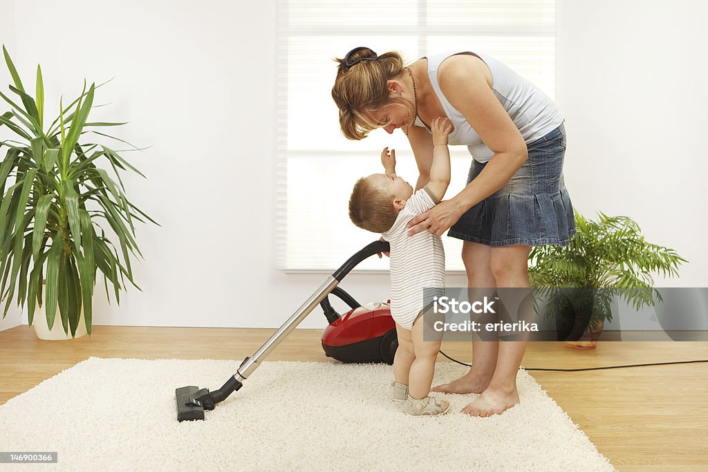 Mother cleaning the floor Mother trying to clean the floor while she's baby is crying and wants to be picked up Baby - Human Age Stock Photo