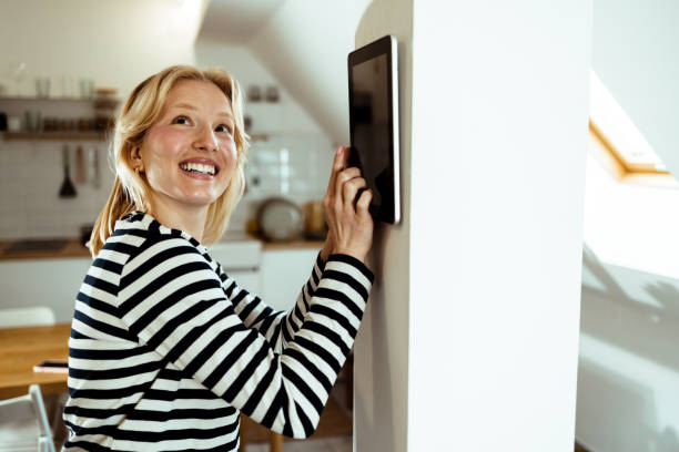 istock Happy young woman adjusting a smart system at her house 1469012365