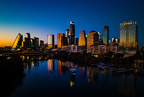 Aerial drone Photography during Blue Hour right after Sunset with dark night time of the Skyline Cityscape and city lights glowing over Town Lake with tall modern skyscrapers rising into the night over Austin , Texas , USA