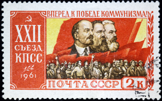 A good example of defunct communist iconography from the Soviet Union, showing Lenin, Engels, and Marx against the red flag and mass of workers.