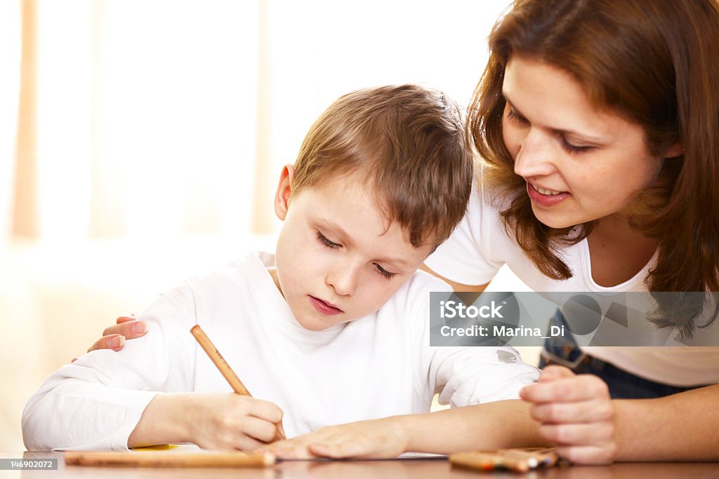 mother helping with homework to her son mother helping with homework to her son indoor; shallow DOF, focus on boys eyes Activity Stock Photo