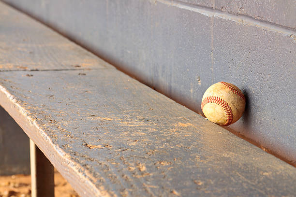 Old Baseball On Dugout Bench An old lone grunge baseball against dugout bench and wall background. baseball baseballs spring training professional sport stock pictures, royalty-free photos & images