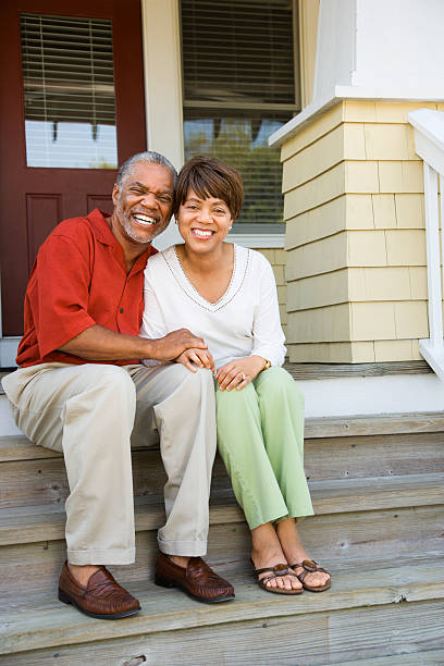 Older couple sitting outside on their front porch steps stock photo